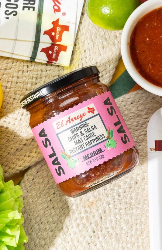Jar of salsa with a pink label on a textured surface